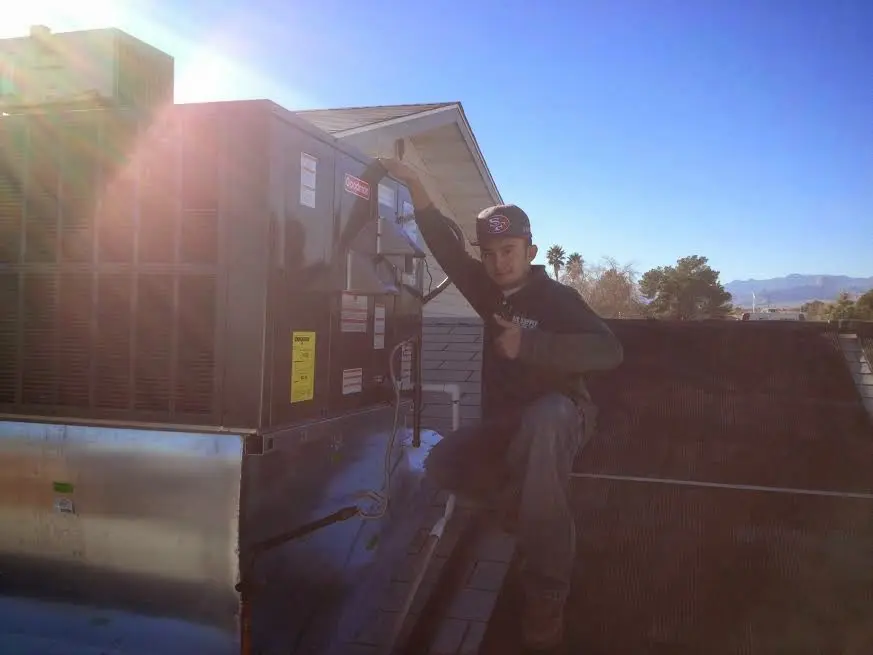 HVAC technician performing Air Duct Cleaning on a rooftop unit in Alexander City